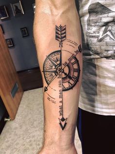 a man's arm with a compass tattoo on it and an arrow in the middle