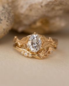 a close up view of a gold ring with a diamond in the center and leaves surrounding it