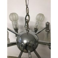 a chrome chandelier hanging from the ceiling with five glass globes on it