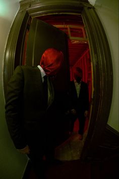 two men in suits and red masks are walking up the stairs to an elevator area