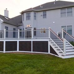 a white deck with railing and stairs in front of a house