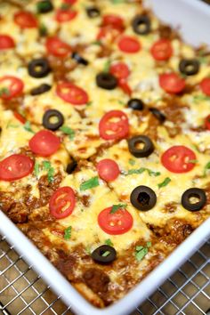 a square casserole dish with tomatoes, olives and cheese on the top