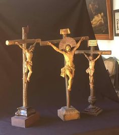 three wooden crucifixs with paintings on the wall in the back ground