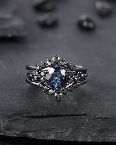 a ring with an oval blue stone surrounded by small white diamonds on top of a rock