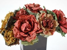 three different colored paper flowers in a vase