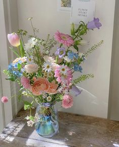 a vase filled with lots of colorful flowers sitting on top of a wooden table next to a door