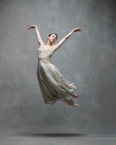 a woman in a white dress is flying through the air with her arms stretched out