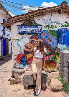 a woman standing in front of a building with graffiti on the wall and walls behind her