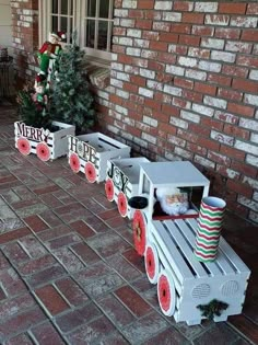 some type of toy train sitting on top of a brick floor next to a christmas tree