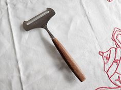 a large metal spatula sitting on top of a white table cloth next to a wooden handle