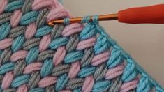 the crochet stitch is being worked on by an orange handled knitting needle,