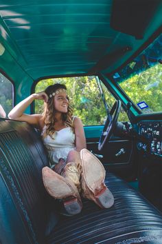 a woman sitting in the driver's seat of a truck with her feet up