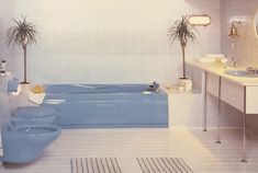 a blue bath tub sitting next to a sink in a bathroom under a mirror and two potted plants