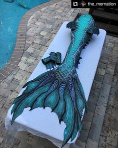 an artisticly designed mattress sitting next to a swimming pool with a fish design on it