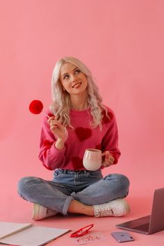 a woman sitting on the floor with her laptop and coffee cup in front of her