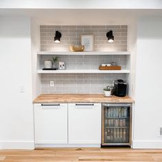 an empty kitchen with white cabinets and wood flooring is pictured in this image, there are shelves on the wall above the refrigerator