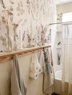 towels and vases are hanging on the wall next to a bathtub in a bathroom