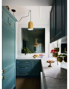 the kitchen is painted in blue and features an antique brass pendant light over the island