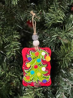 a christmas tree ornament hanging from a pine tree with ornaments on the branches