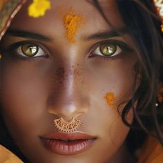 a woman with yellow paint on her face and nose is wearing an elaborate nose ring