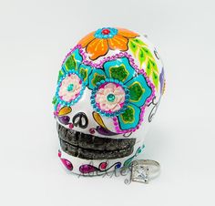 a brightly colored sugar skull with flowers on it's head and a pair of scissors