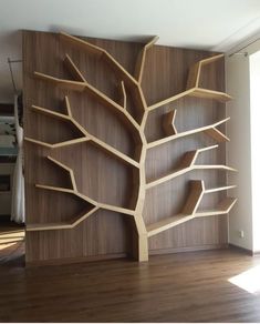 a wooden bookcase with shelves and a tree on the wall