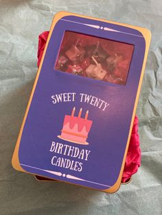 a birthday cake with candles on it sitting in a pink box that says sweet twenty birthday candles