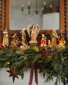 a mantel with christmas decorations and angel figurines