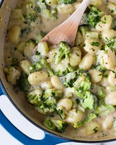 broccoli and macaroni soup in a blue pot with a wooden spoon