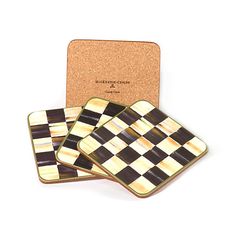 three square coasters with black and white checkers on the front, one in gold