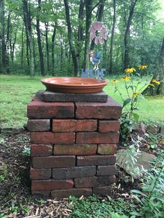 a planter sitting on top of a brick wall in the middle of a forest