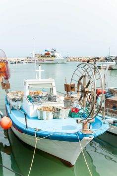 a blue and white boat docked at a pier with other boats in the water behind it