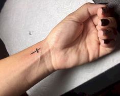 a woman's hand with a small cross tattoo on the middle of her wrist