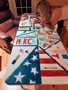 a woman is painting an american flag on a table