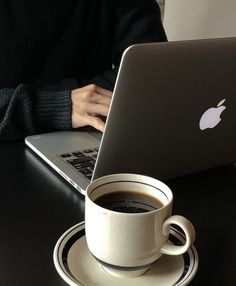 a person sitting at a table with a laptop and cup of coffee in front of them