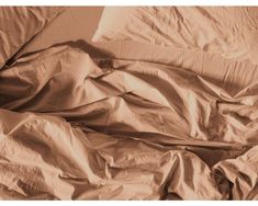 an unmade bed with sheets and pillows on top of it in sepia tone