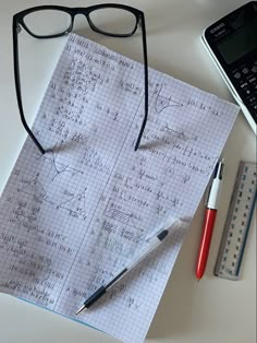 a notebook with writing on it next to a calculator, pen and eyeglasses