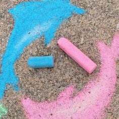 two crayons are laying on the ground next to chalk