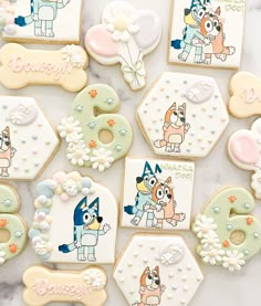 decorated cookies with dogs and flowers are arranged on a marble countertop for a birthday party