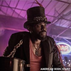 a man wearing a top hat and holding a drum in front of a purple light