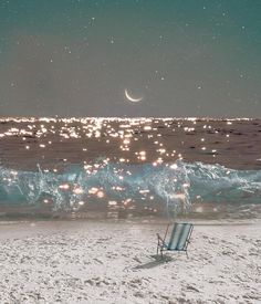 a beach chair sitting on top of a sandy beach next to the ocean under a full moon