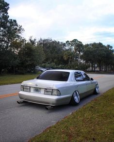 a silver car parked on the side of a road next to a lush green field