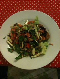 a white plate topped with salad on top of a red and white checkered table cloth