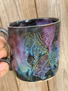 a hand holding a purple and blue coffee mug