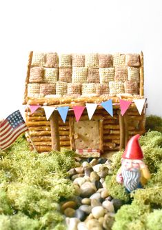 a small house made out of logs and grass with flags on the roof next to it