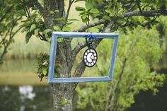 a small blue frame hanging from a tree