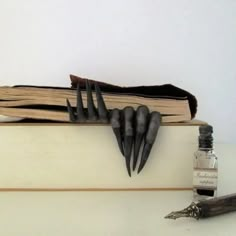 an old book with black nails on it and a bottle of ink next to it