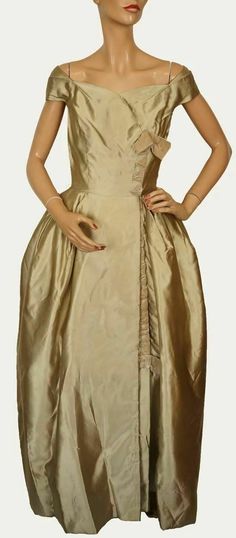 A 1940s evening gown, this is a rare piece by Bianca Gusmaroli, a Canadian couturier.  There are probably not too many examples of Bianca Gusmaroli's work that have managed to survive, so this is really a collector's piece, deserving of museum display. The gown is made of champagne gold colored silk in an off-the-shoulder style. It has a sweetheart neckline, with the right side crossing over the left front, the separation accented down the line with mustard tan colored velvet ribboning. The inte Vintage A-line Formal Dress, Vintage A-line Dress For Formal Occasions, Formal Fitted Vintage Dress, Vintage Lined Evening Dress, Victorian Vintage Dress With Fitted Bodice For Formal Events, Classic Vintage Dress With Ruffles For Formal Occasions, 1950s Style Vintage Dress For Events, Elegant Vintage Dress For Vintage Events, Vintage Ball Gown Evening Dress With Fitted Bodice