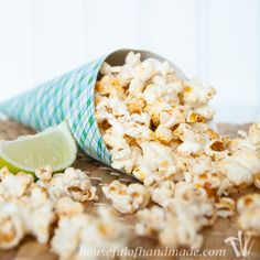 a cup filled with popcorn sitting on top of a table next to a lime slice