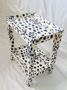 a white and blue painted wooden table on a white sheeted surface with black dots